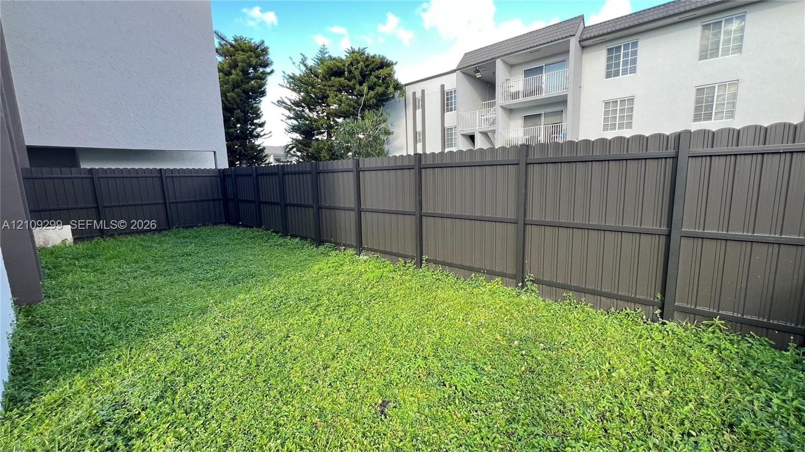 Private outdoor space featuring a dark-toned vertical slat privacy fence and a grassy yard
