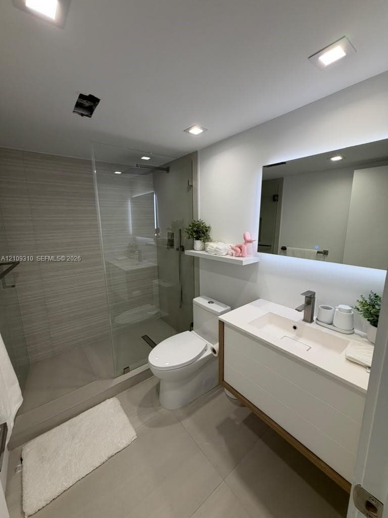 Walk-in shower with horizontal tile surround and glass partition, floating vanity featuring a rectangular integrated sink, white countertop, and LED-backlit mirror