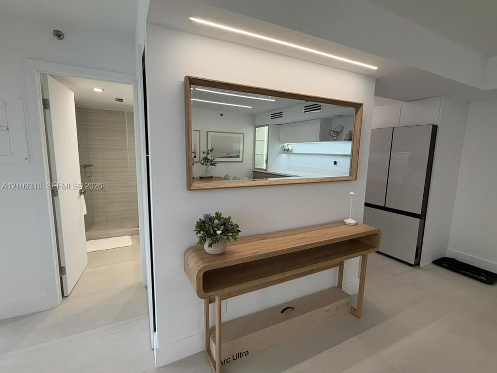Neutral interior featuring integrated linear lighting, a recessed mirror, and high-gloss cabinetry