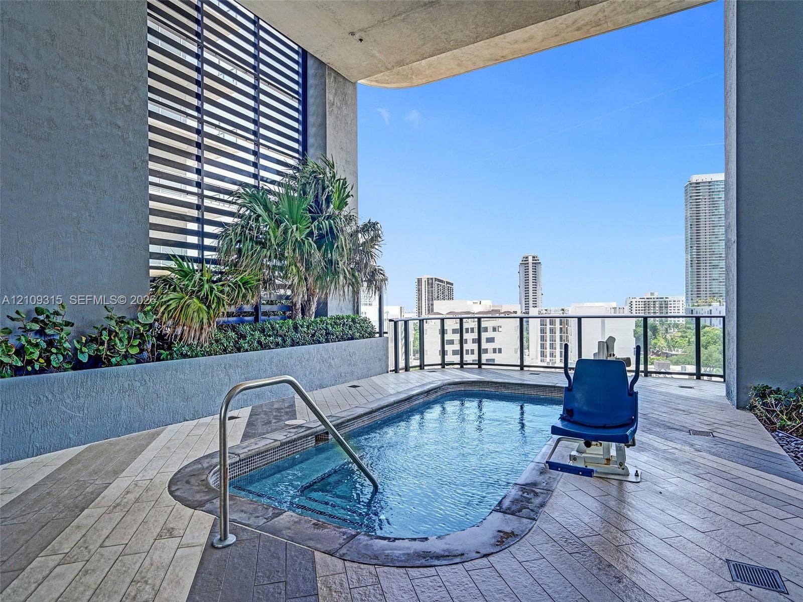 Covered outdoor pool featuring tile flooring in a herringbone pattern, integrated raised concrete planters, stainless steel handrail, and black metal railings