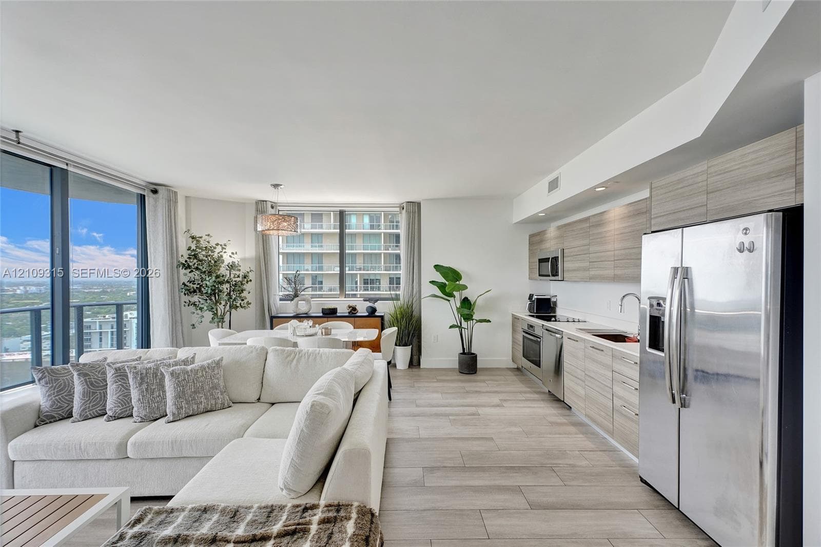 Open-concept kitchen featuring horizontal-grain wood-finish cabinetry, stainless steel appliances, and wood-finish tile flooring throughout