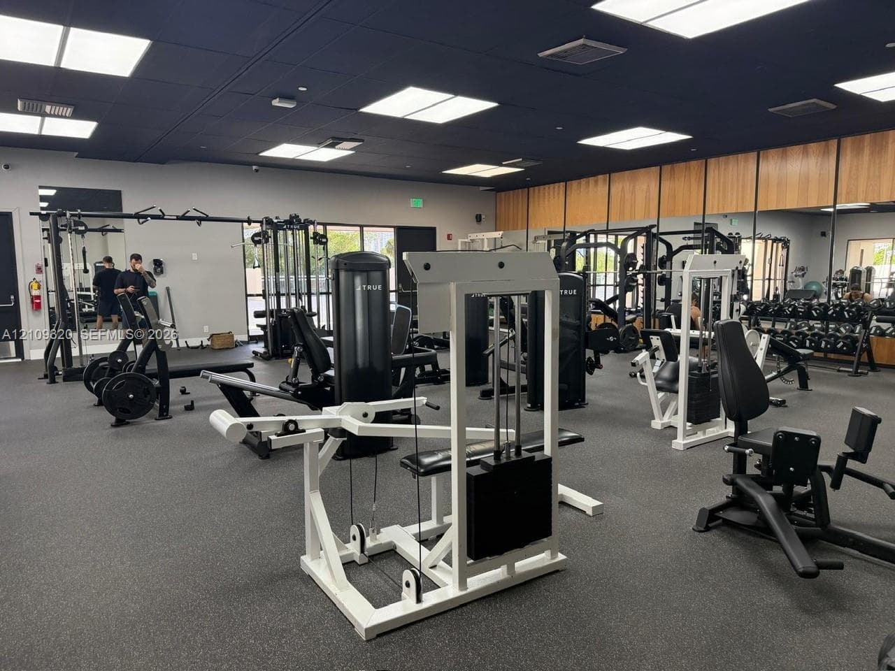 Fitness facility featuring expansive mirrored walls, high-contrast black ceiling panels, recessed lighting, and rubberized flooring