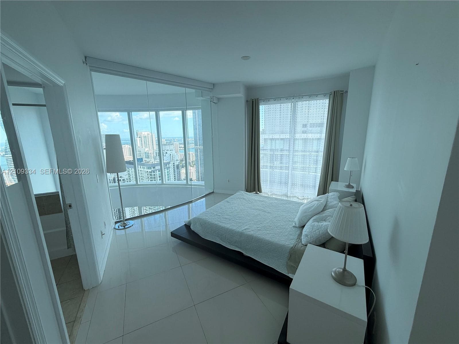 Floor-to-ceiling curved glass windows, expansive ceramic tile flooring, and neutral wall finishes