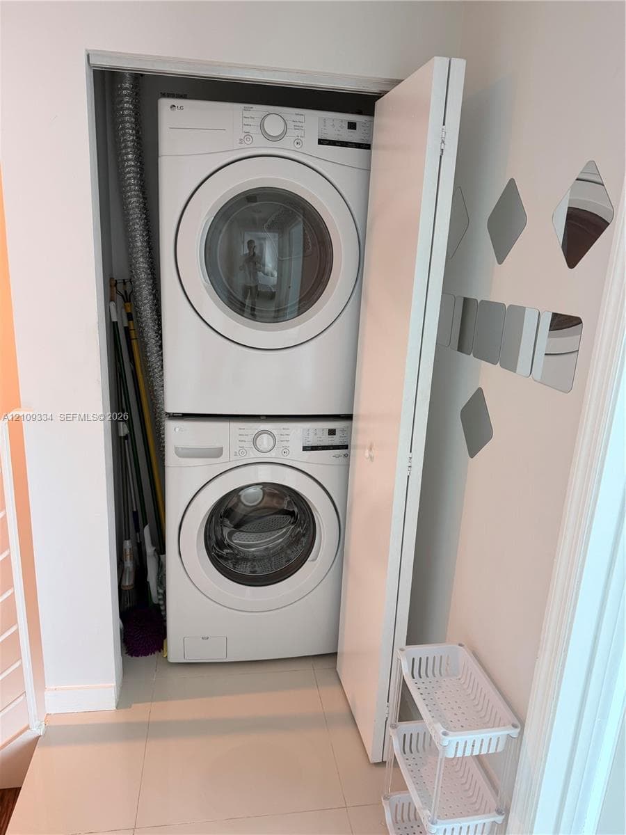 Stacked LG front-loading washer and dryer unit enclosed in a dedicated laundry closet with large-format tile flooring