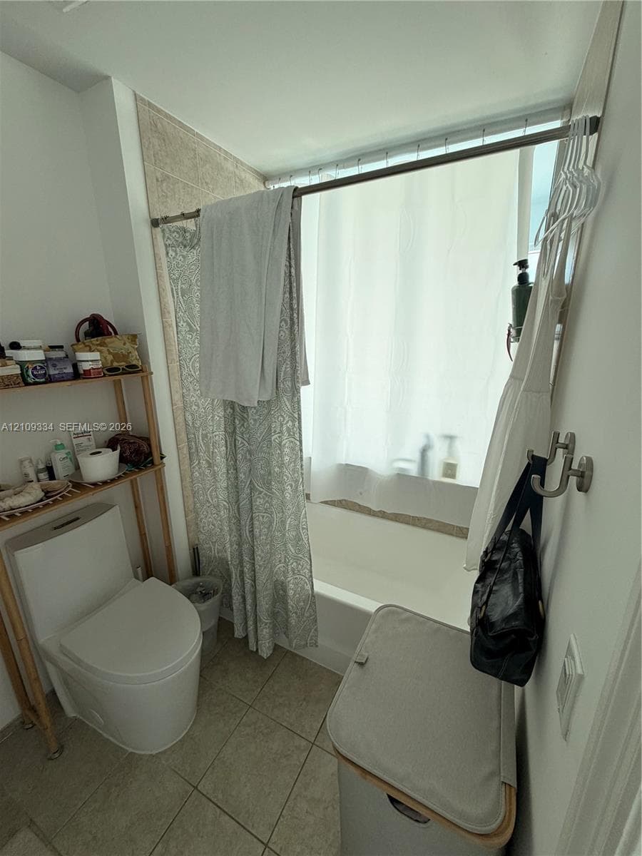 Bathroom featuring a soaking tub, neutral tile flooring, and wall-mounted metal hardware