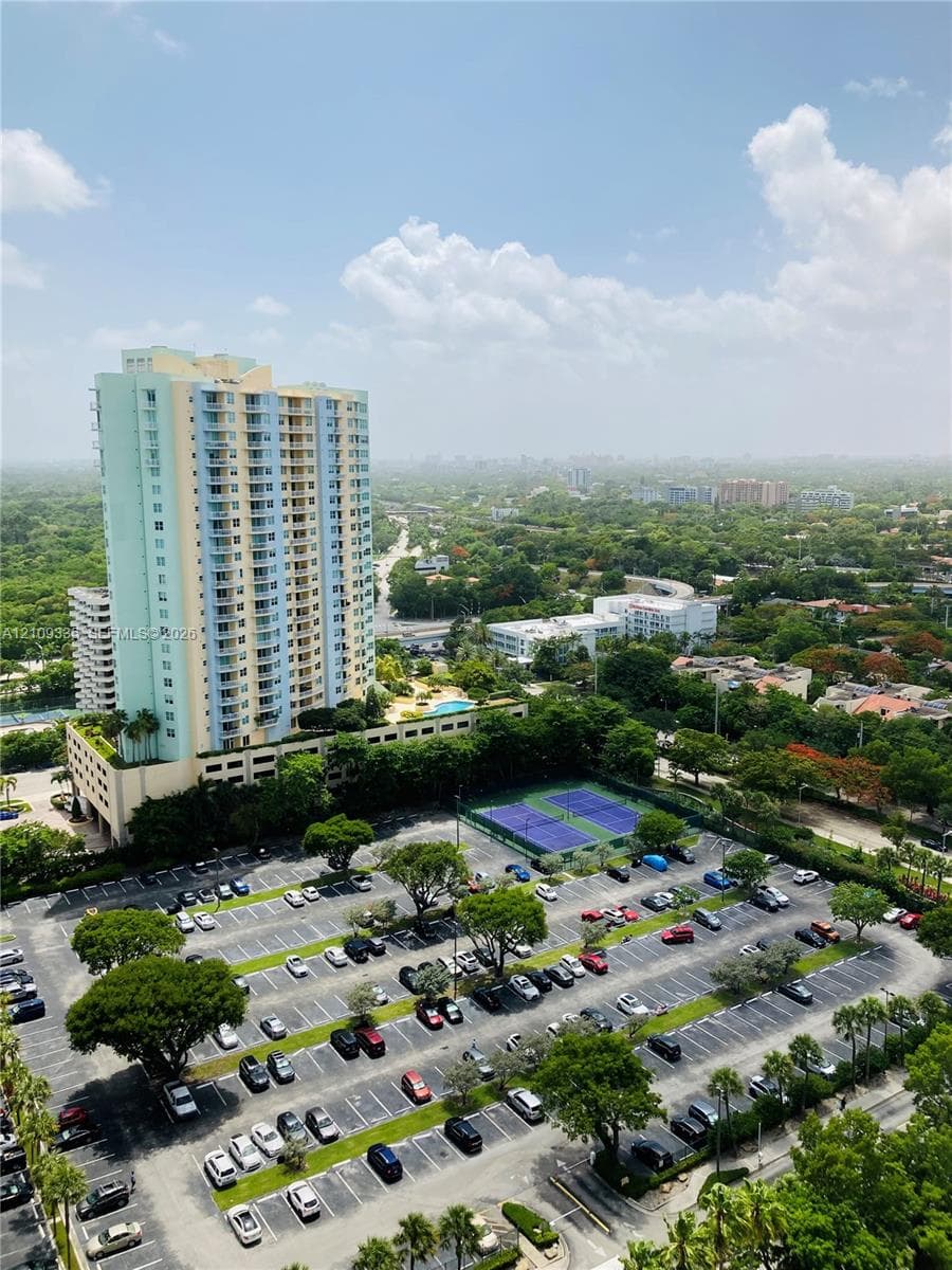 High-rise residential complex featuring a paved parking area and an on-site tennis court