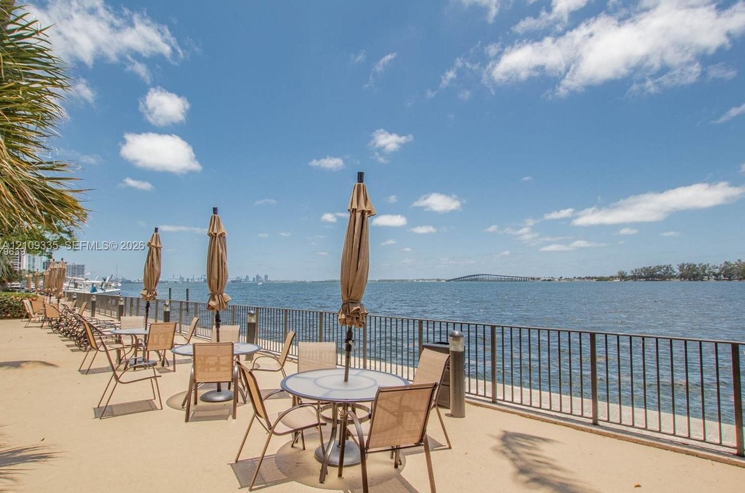 Waterfront terrace featuring a paved surface, metal perimeter railing, and direct water access