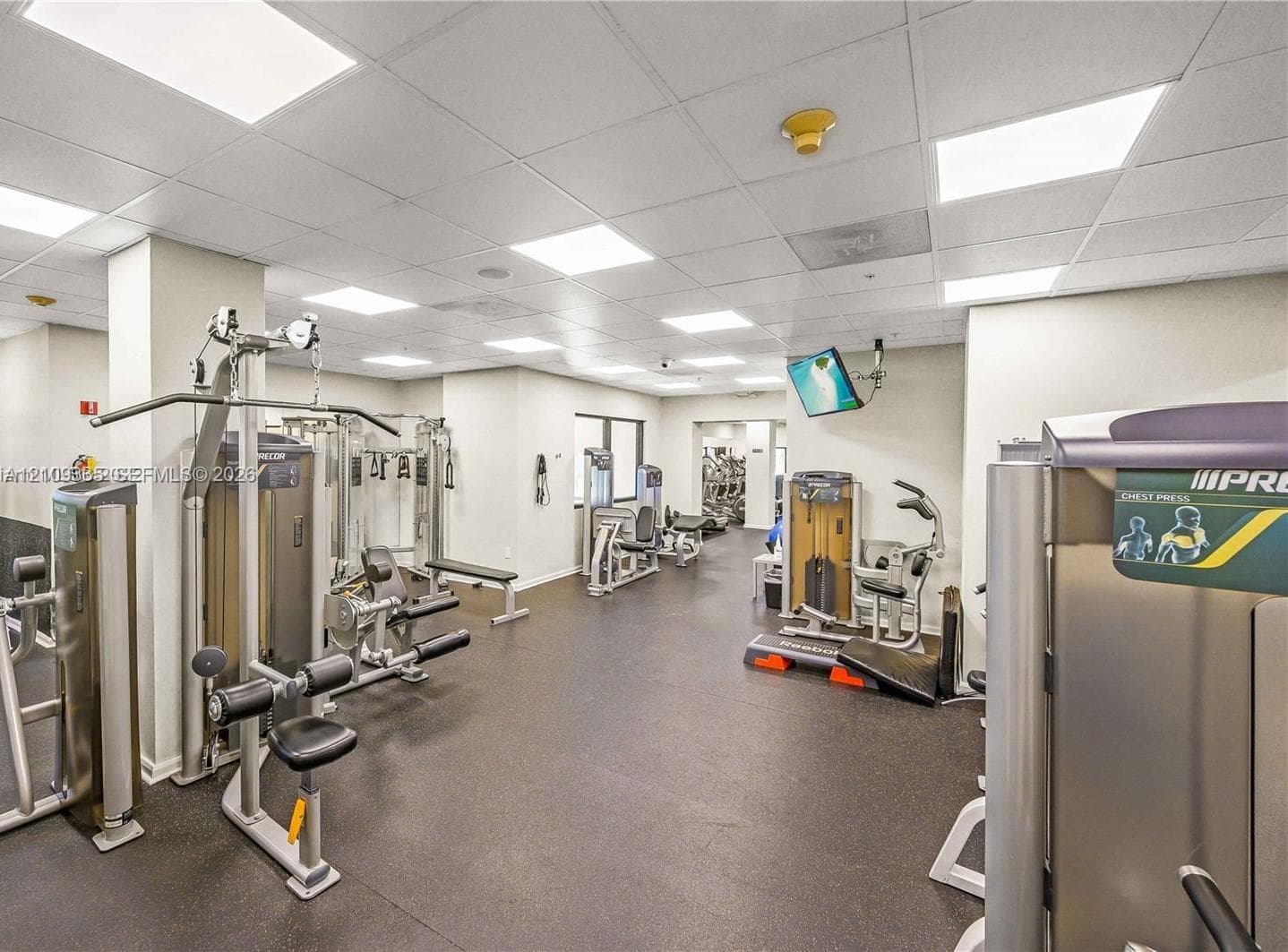 Fitness facility featuring rubber flooring, drop ceiling with recessed lighting, and integrated wall-mounted speakers