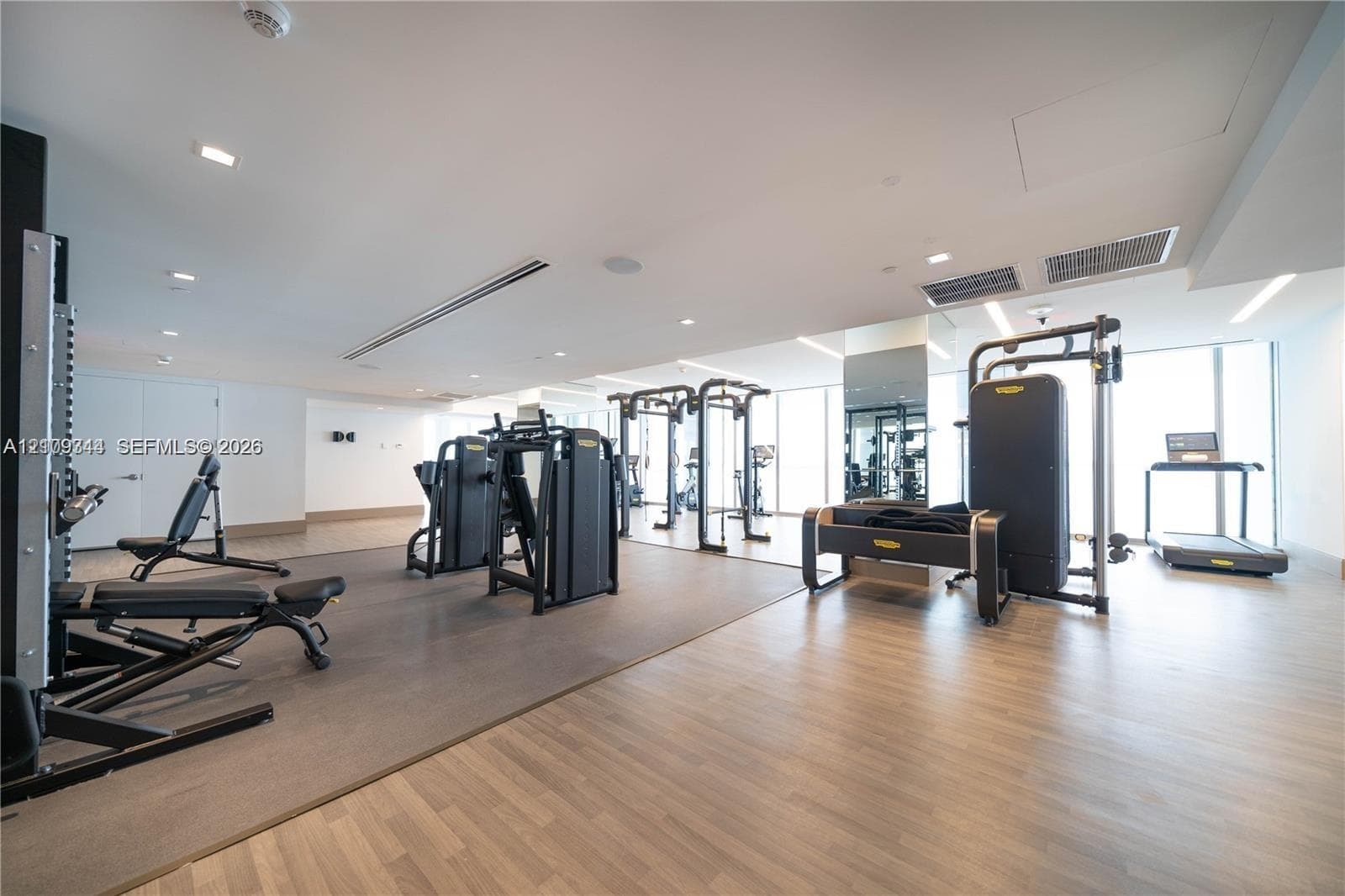 Fitness center featuring wood-finish flooring, floor-to-ceiling windows, recessed lighting, and mirrored walls