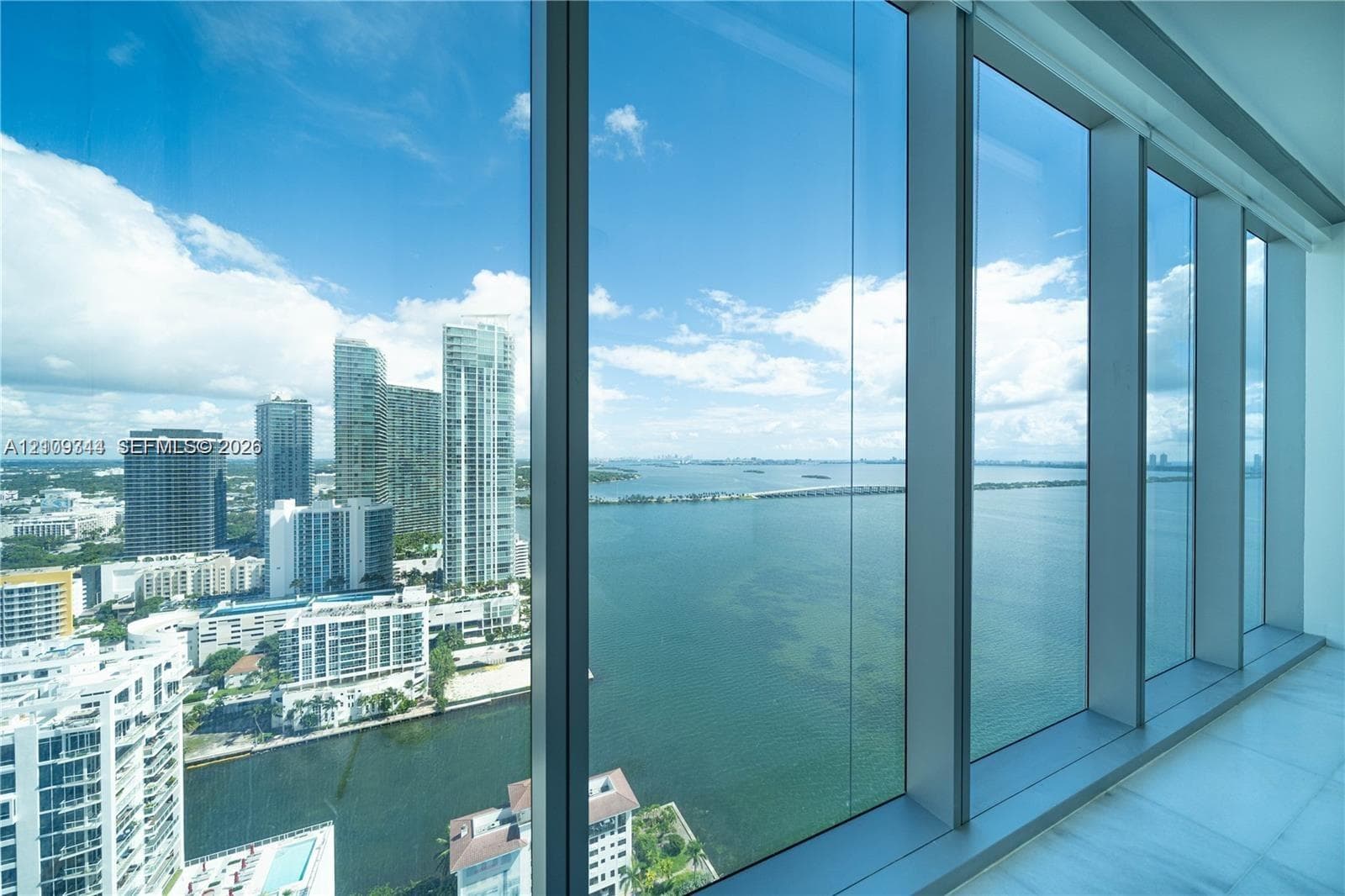 Floor-to-ceiling glass curtain wall with metallic framing and white stone flooring