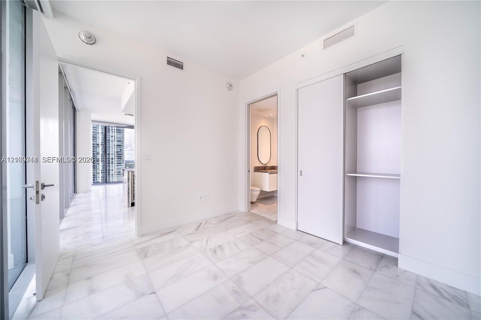Interior space featuring light-toned stone-finish flooring, floor-to-ceiling glass wall, and built-in closet with sliding doors
