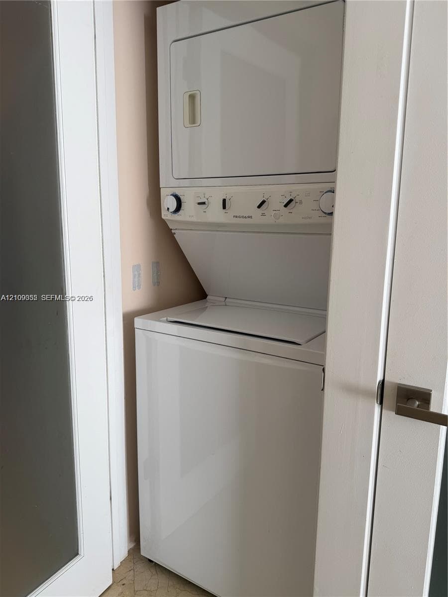 Stacked laundry center featuring a white top-loading washer and integrated dryer
