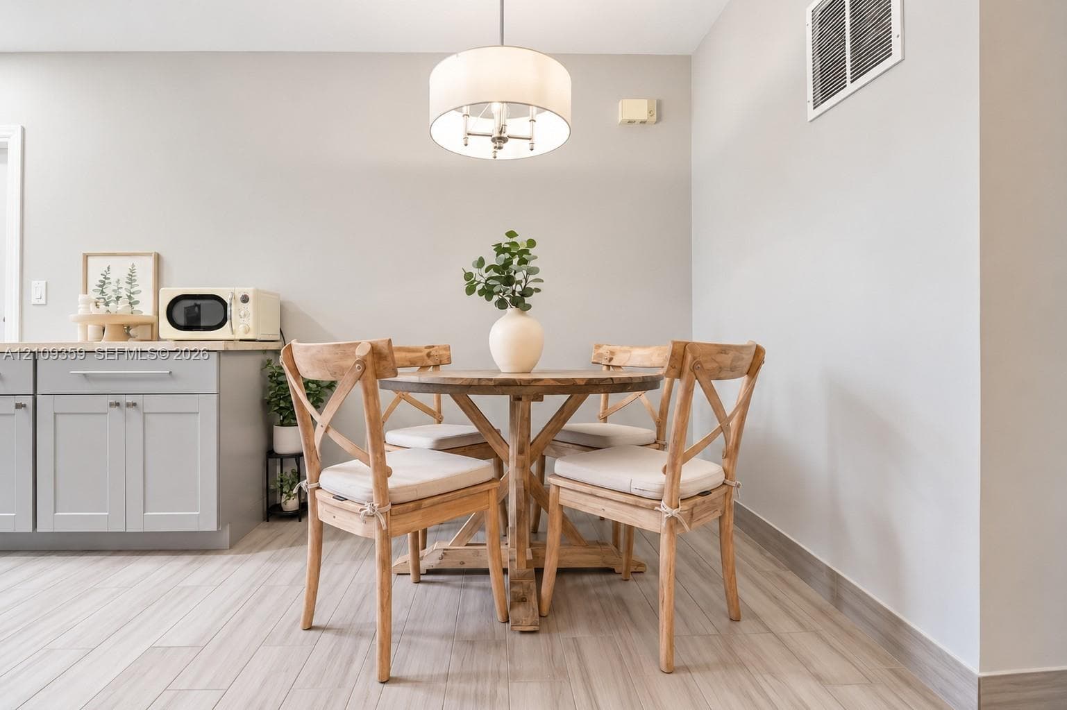Light gray cabinetry with stone-finish countertops, tile flooring, and a drum-style pendant light fixture