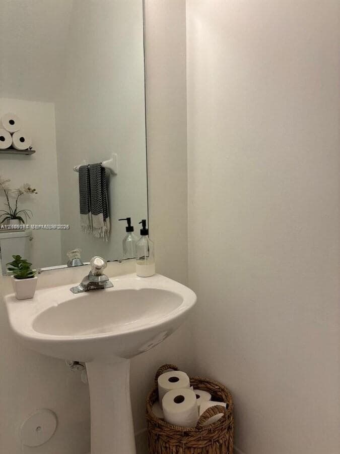 White pedestal sink with a chrome finish faucet and a floor-to-ceiling mirror