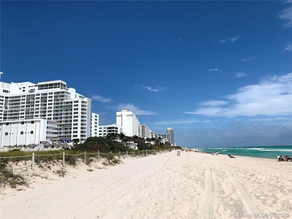 Direct beach access with sandy shoreline, coastal dunes, and proximity to oceanfront high-rise structures