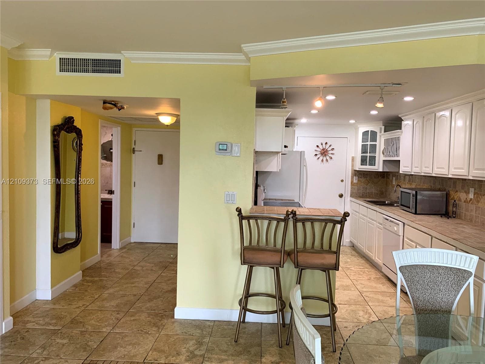 Kitchen featuring white shaker-style cabinetry, tile backsplash, tile flooring, and integrated track lighting