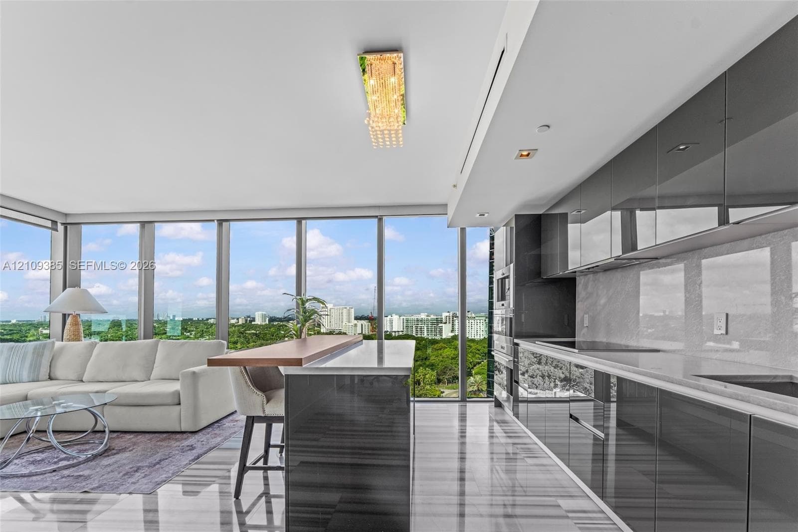 Kitchen featuring high-gloss cabinetry, stone countertops, integrated appliances, floor-to-ceiling windows, and polished stone flooring
