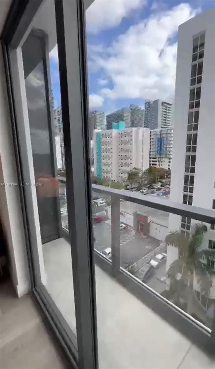 Balcony featuring full-height sliding glass doors, a metal railing, and concrete flooring
