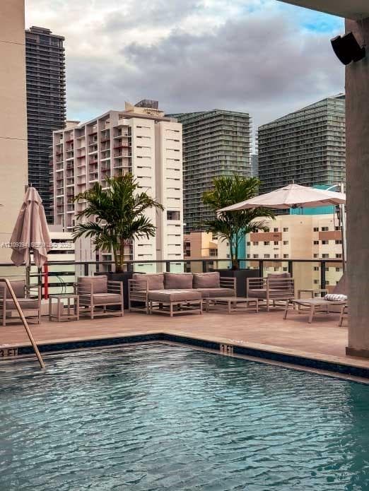 Rooftop swimming pool with tile-accented edge, paved deck, integrated planters, and metal railing
