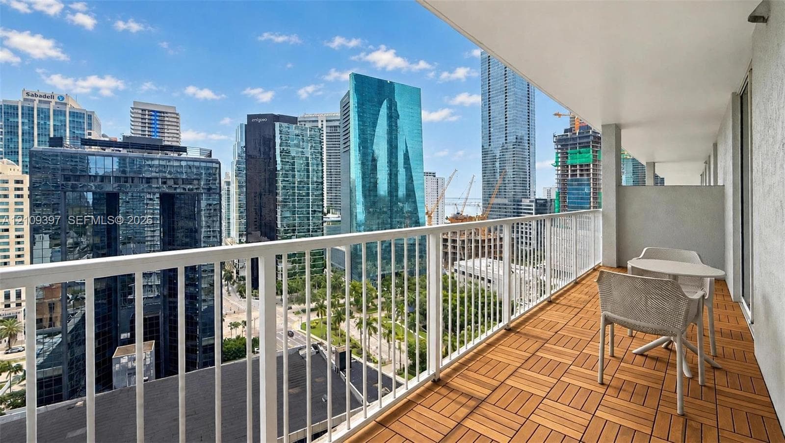Covered balcony featuring wood-finish deck tiling and white metal railing