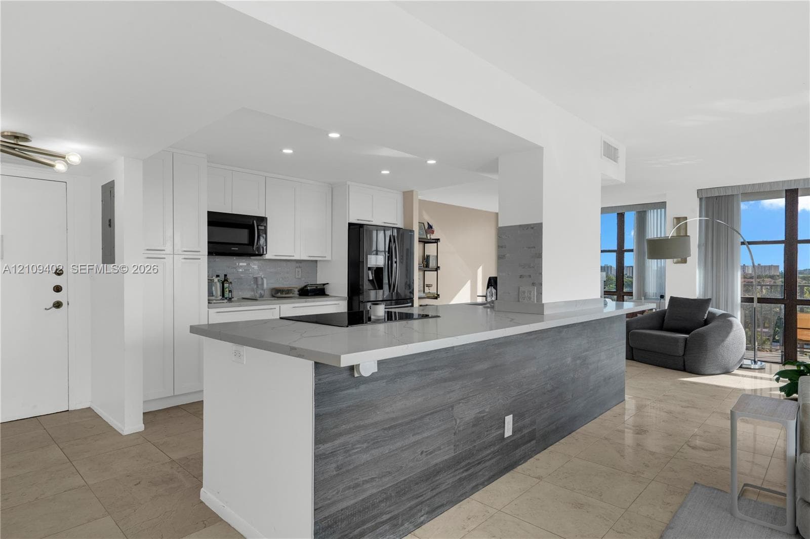 Kitchen featuring white cabinetry, quartz countertops, a stone-finish island base, recessed lighting, and tile flooring