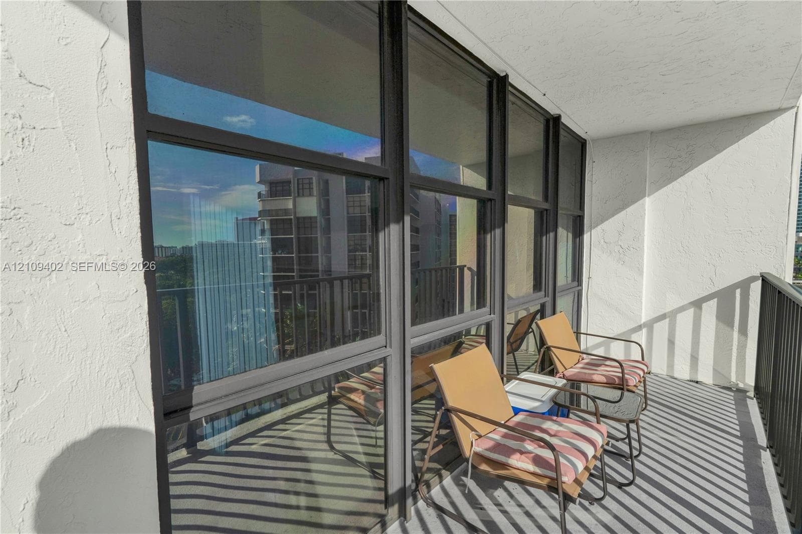 Balcony featuring full-height glass windows with dark frames, textured walls, and a metal railing