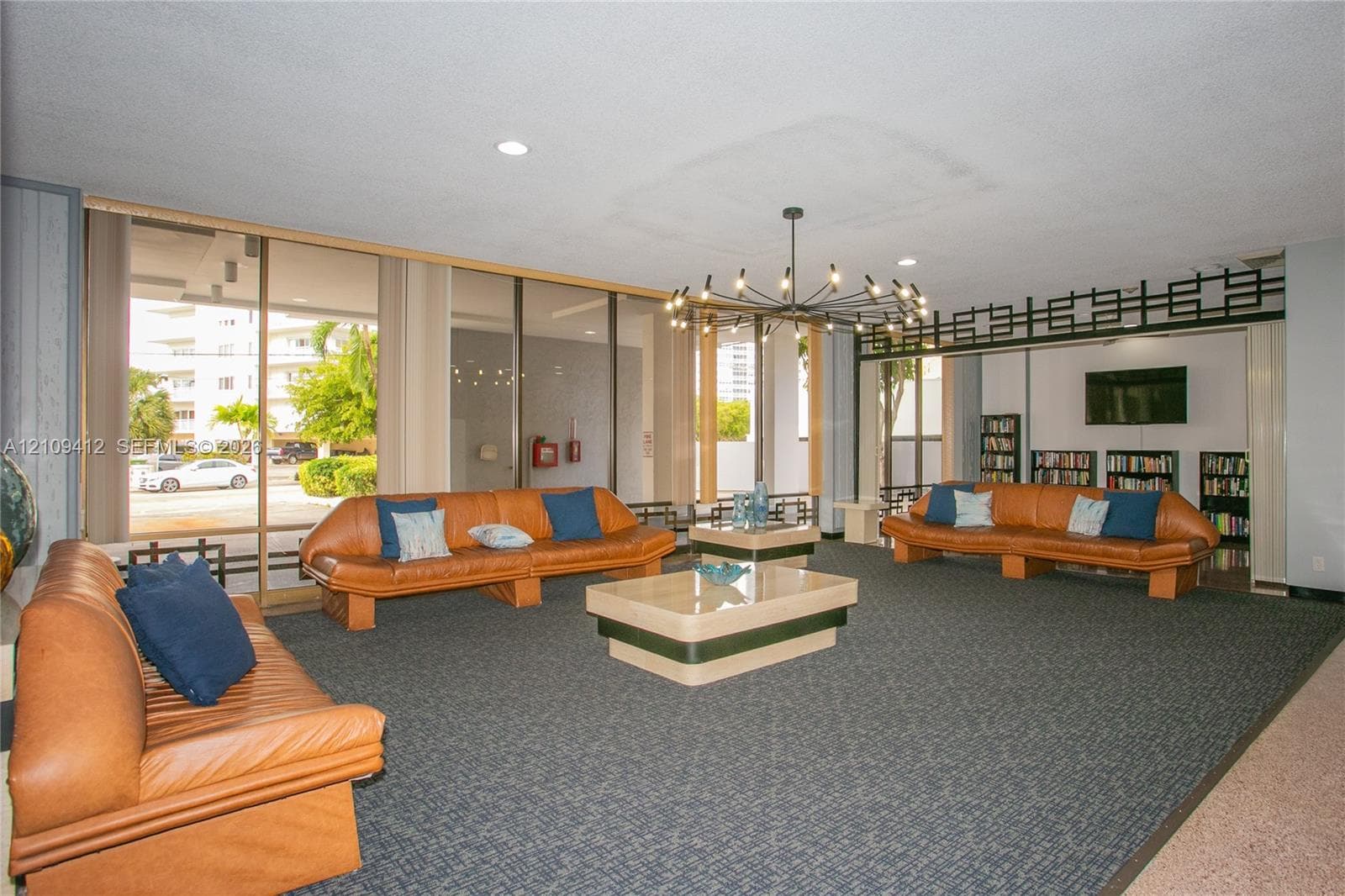 Common area featuring floor-to-ceiling glass windows, a decorative geometric lattice screen, a multi-arm chandelier, and wall-to-wall carpeting