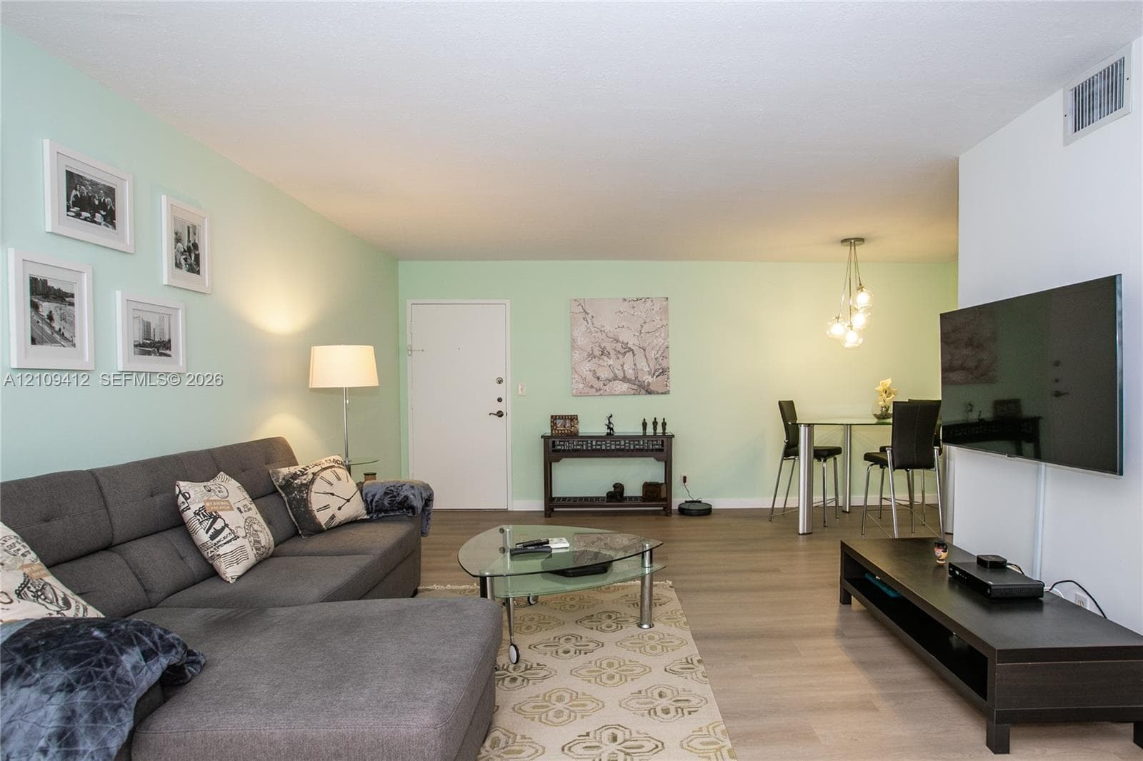 Open-concept interior featuring wood-finish flooring and a multi-pendant light fixture