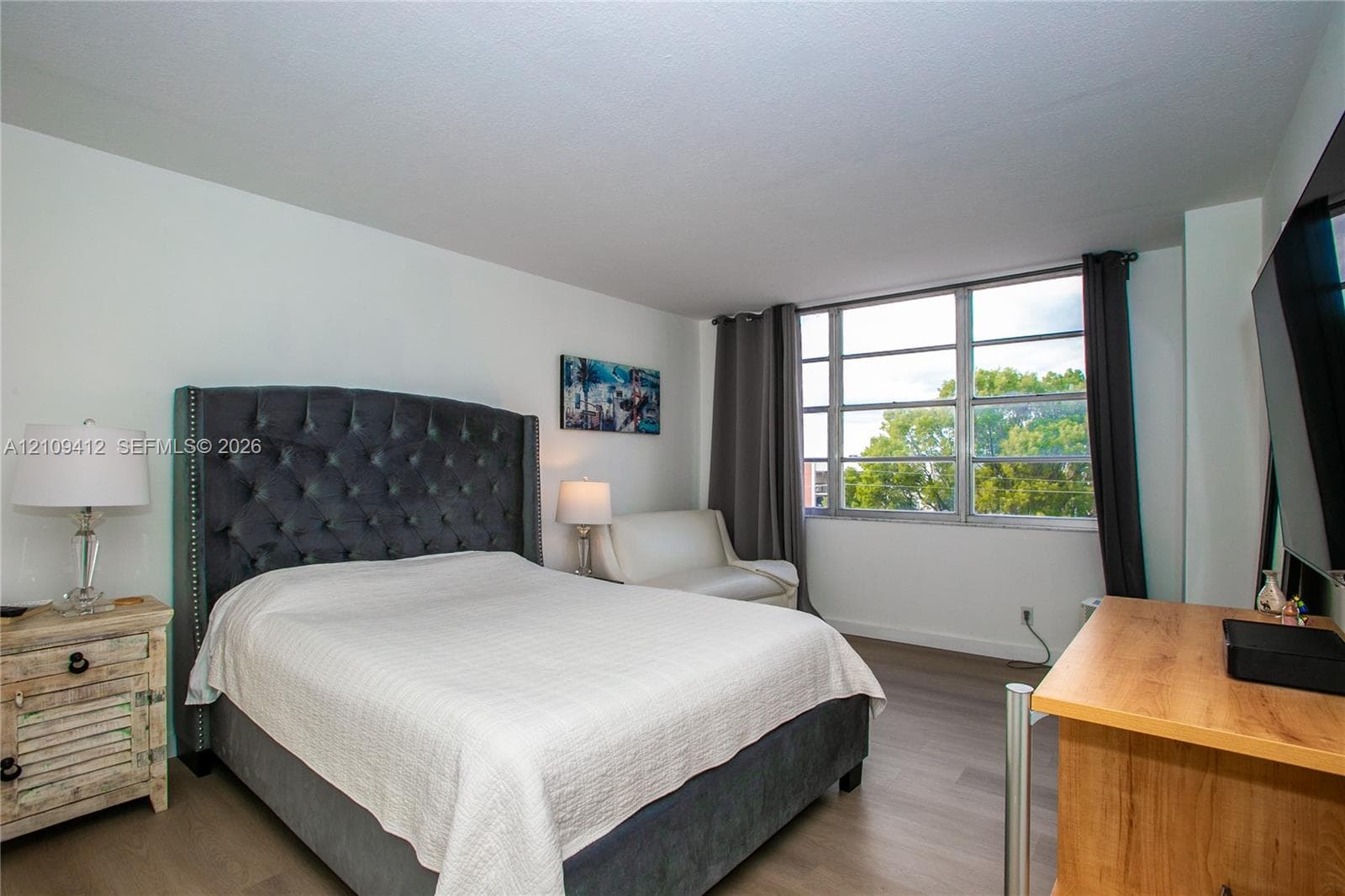 Room featuring wood-finish flooring, a large multi-pane window, and neutral walls