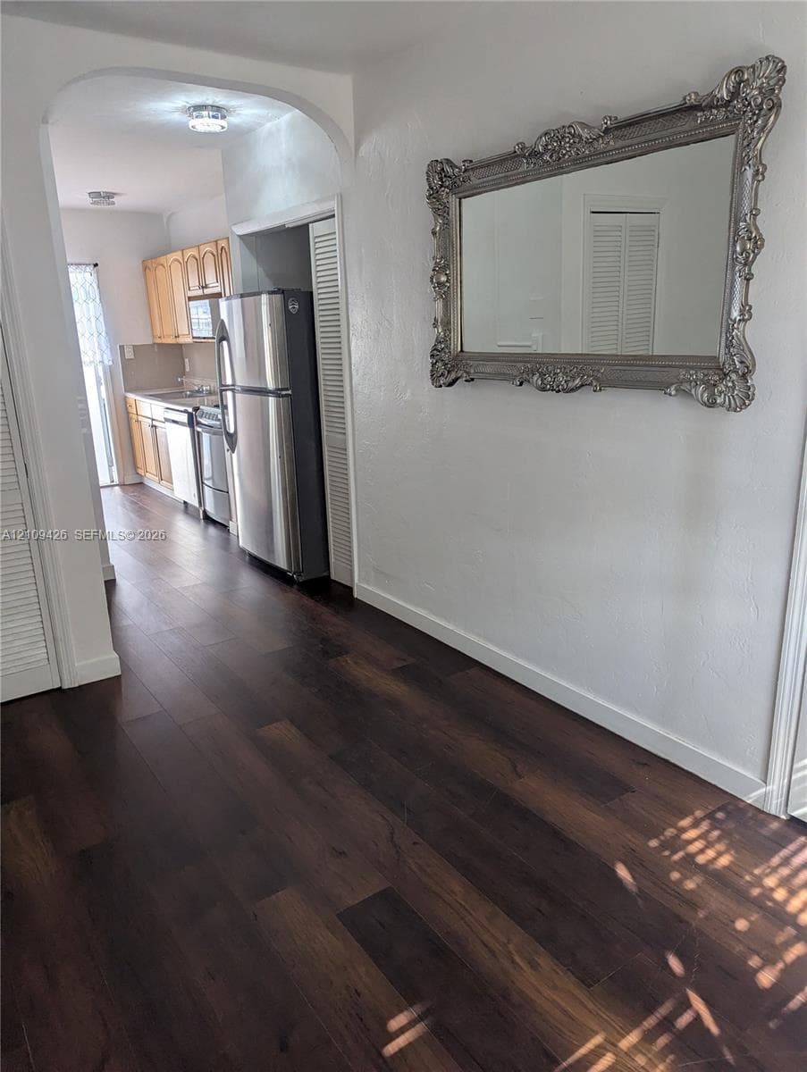 Interior featuring dark wood-finish flooring, an arched entryway, louvered closet doors, and recessed lighting