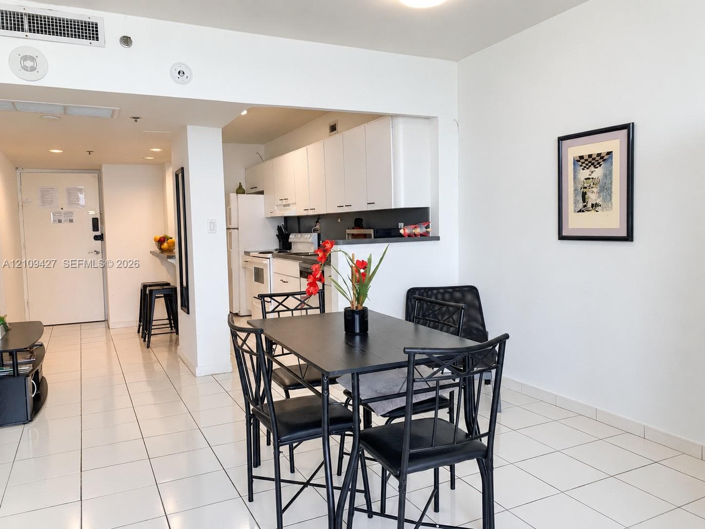 Kitchen featuring white cabinetry and built-in appliances, ceramic tile flooring, and a breakfast bar