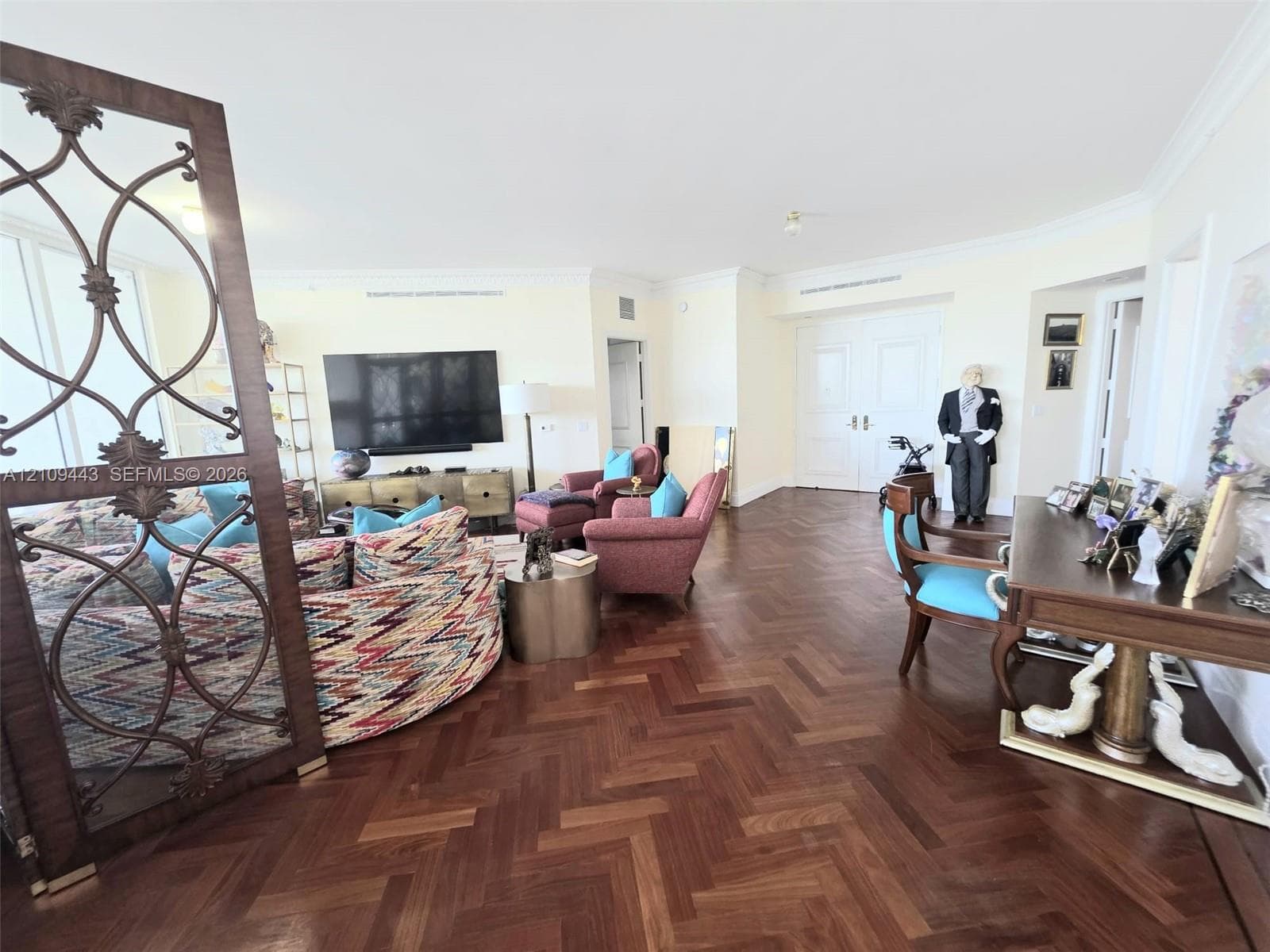 Herringbone-patterned wood-finish flooring, decorative metal room divider, and double-door entry