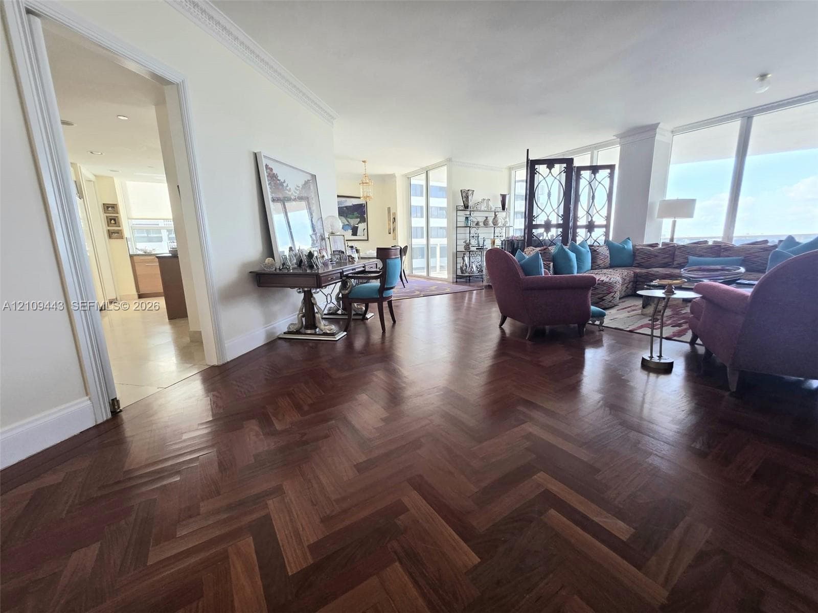 Herringbone wood-finish flooring, floor-to-ceiling windows, and decorative crown molding