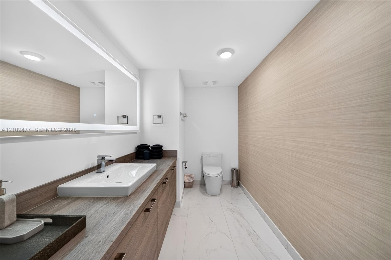 Covered balcony featuring wood-finish flooring, glass panel railings, frosted privacy screens, and floor-to-ceiling sliding glass doors