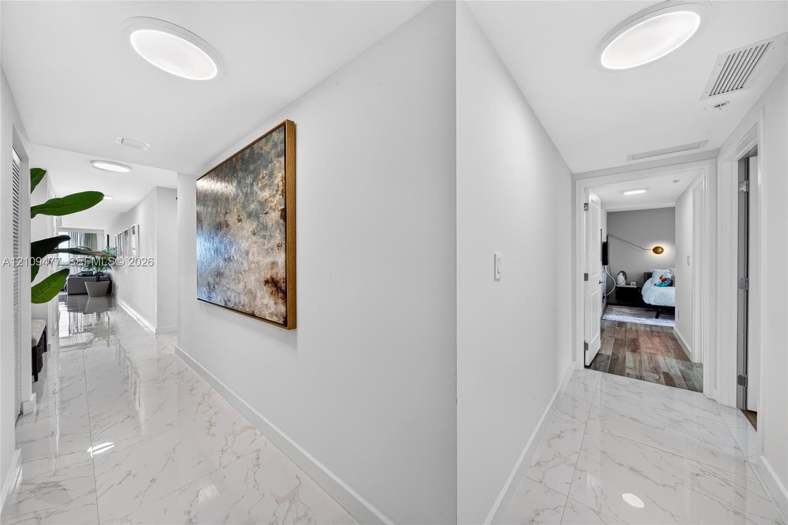 Open-concept interior featuring light-toned flooring, modern kitchen cabinetry with a central island, recessed lighting, and floor-to-ceiling glass sliding doors