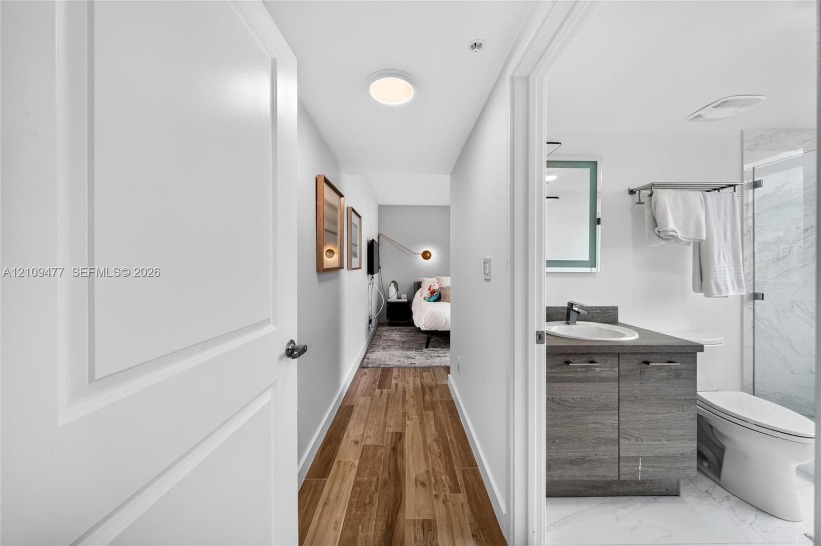 Private balcony featuring wood-finish tile flooring, a glass-panel railing, and frosted privacy partitions