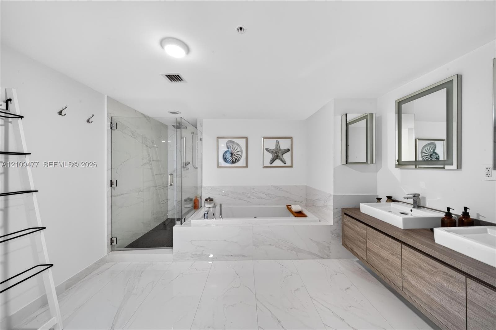 Kitchen featuring custom cabinetry with horizontal wood-grain finish, contrasting white lower cabinets, extended peninsula with wooden waterfall countertop, stone-finish tile flooring, and stainless steel built-in appliances