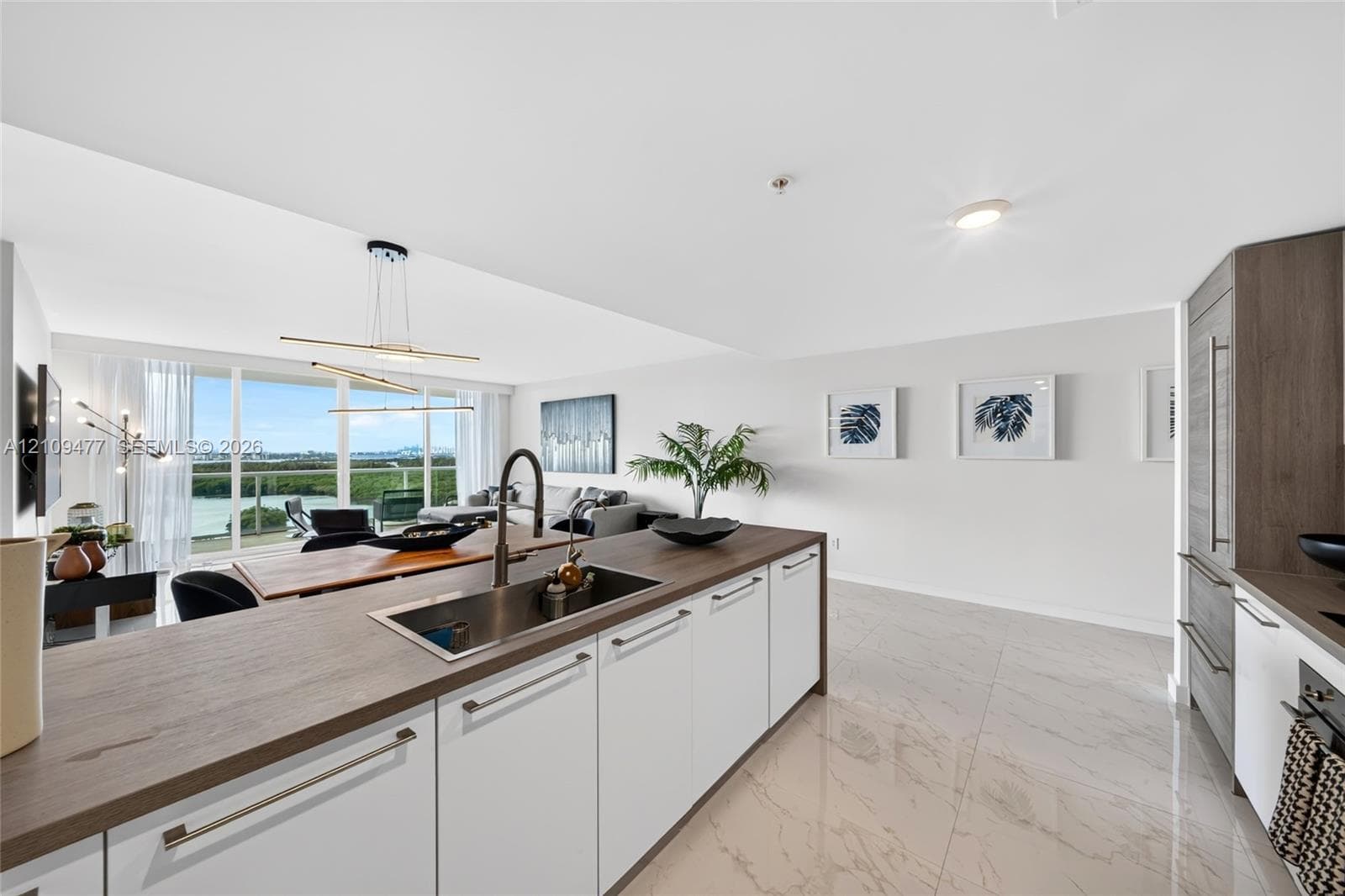Laundry closet featuring stacked front-load appliances and louvered folding doors, accented by polished stone-finish flooring and recessed lighting