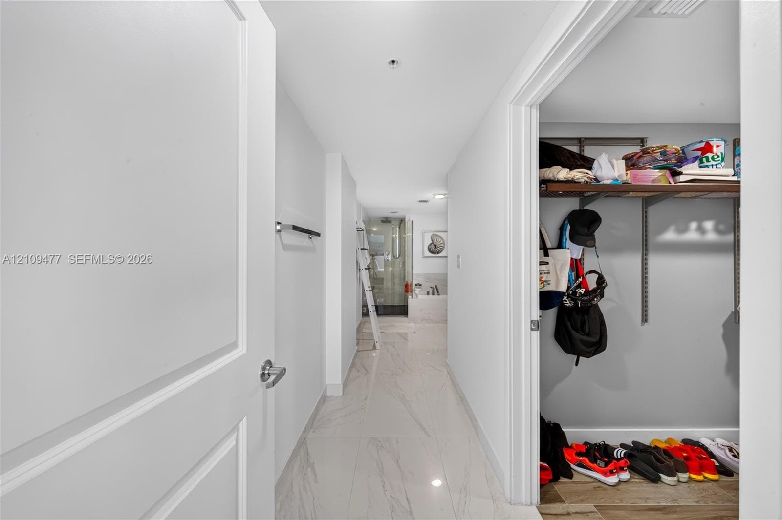 Kitchen featuring a central island with a wood-finish countertop, stainless steel undermount sink, high-arc faucet, white cabinetry with horizontal hardware, and large-format tile flooring