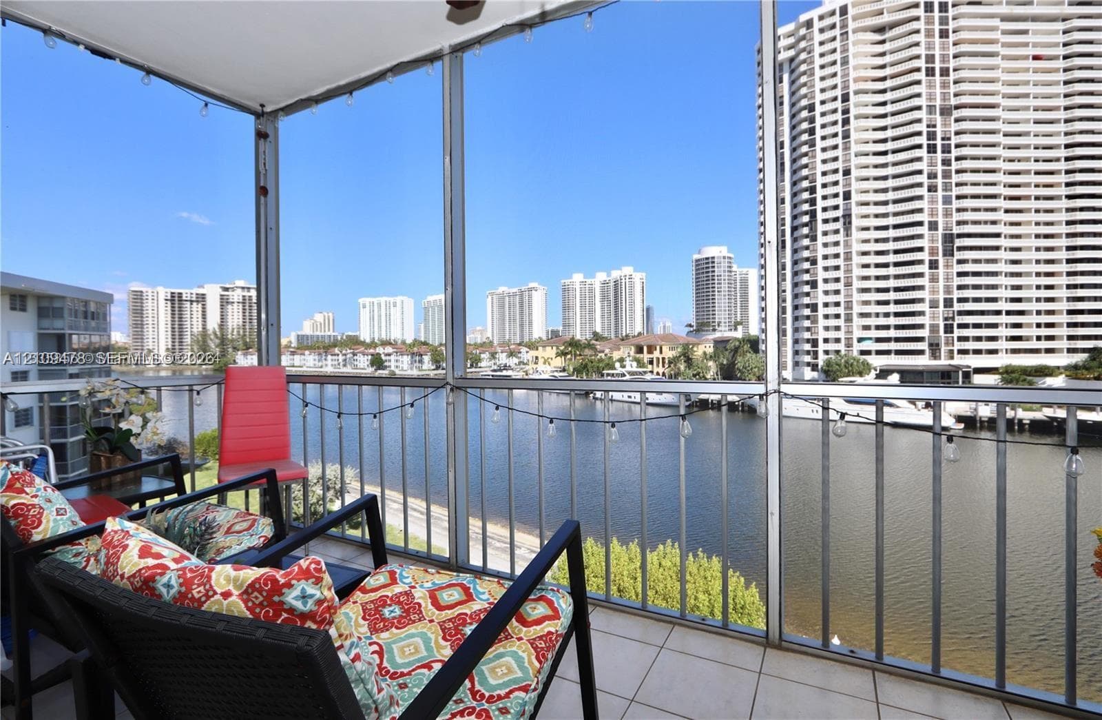 Screened balcony featuring tiled flooring, metal railings, and waterfront exposure