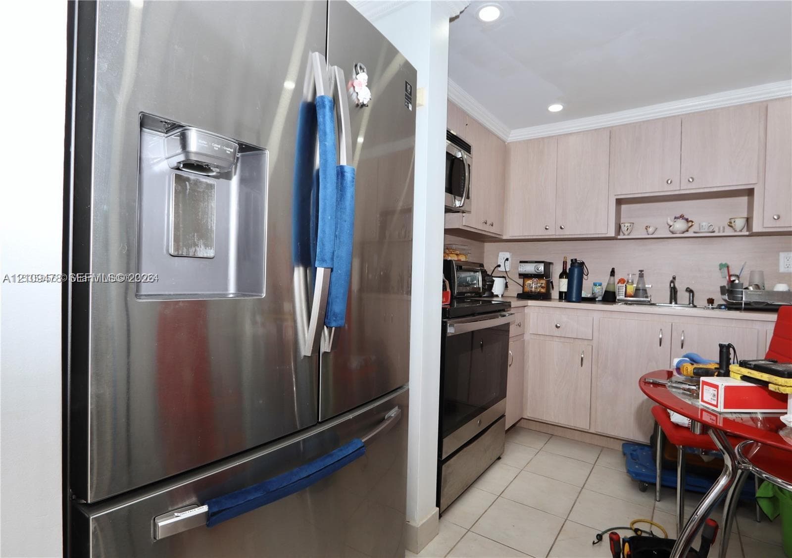 Stainless steel French door refrigerator with exterior water and ice dispenser, light-toned cabinetry, recessed lighting, and tile flooring