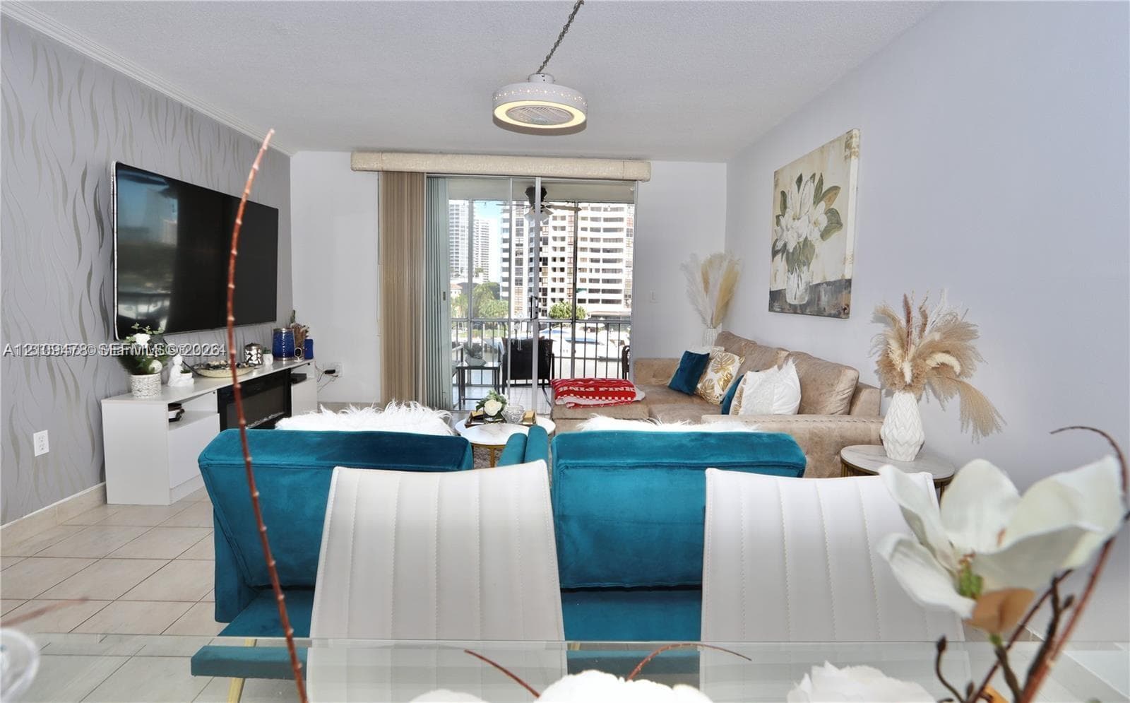 Living area featuring large-format ceramic tile flooring, a textured accent wall, a circular pendant light fixture, and a sliding glass door providing external access