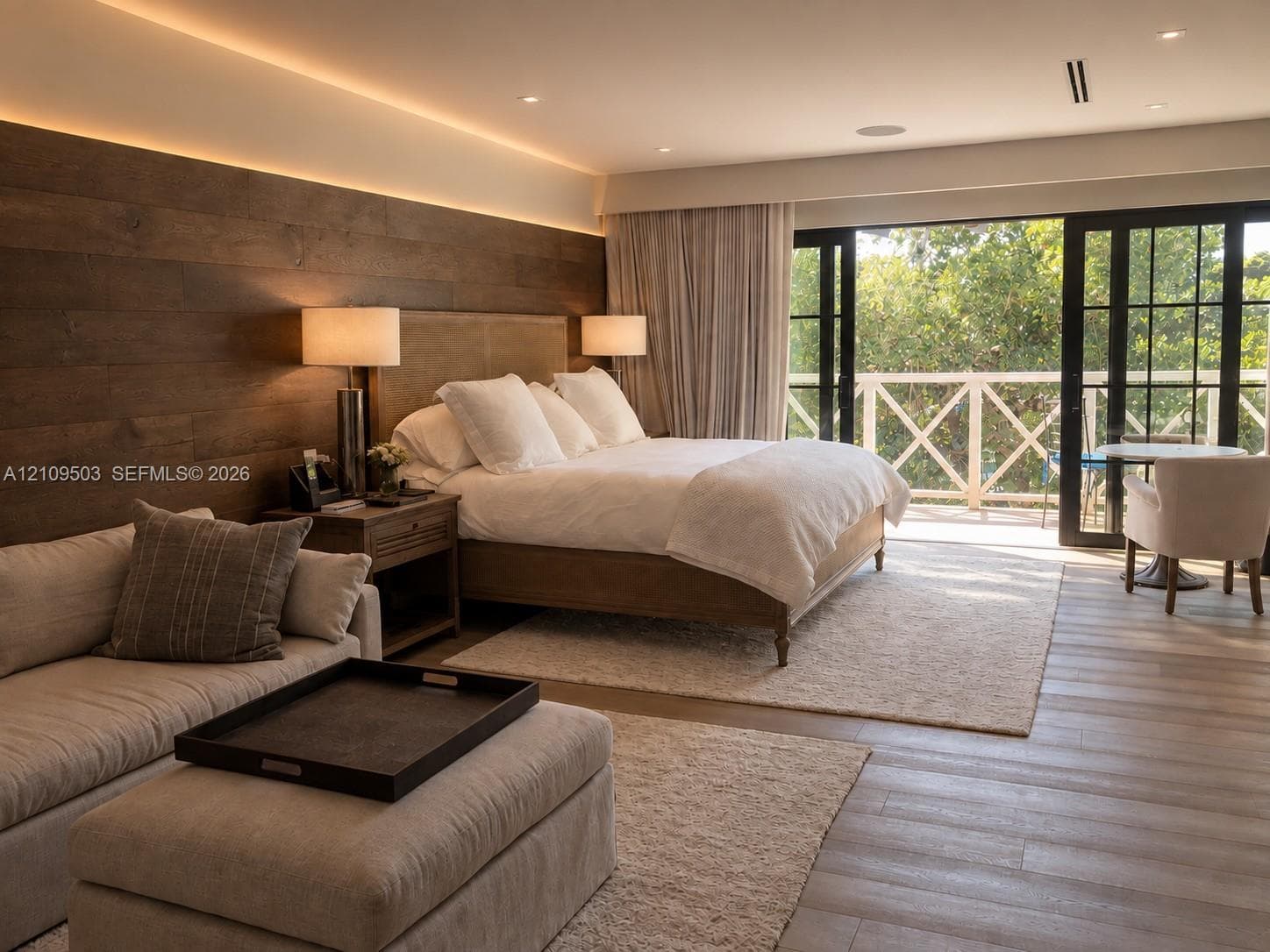 Wood-plank feature wall with recessed accent lighting, wood-finish flooring, and black-framed multi-panel glass doors leading to an exterior balcony