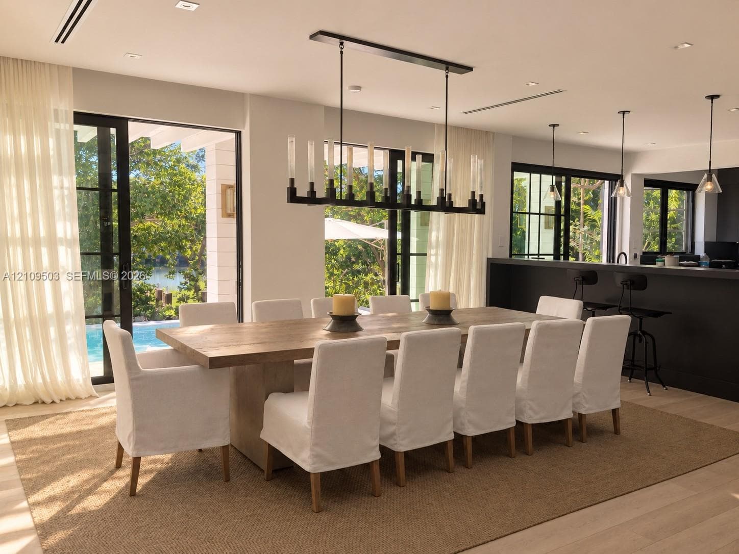 Dining area featuring large-format sliding glass doors, a linear wrought iron chandelier, recessed lighting, wood-finish flooring, and a built-in kitchen island