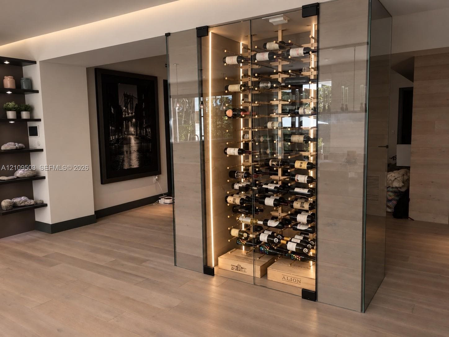 Floor-to-ceiling glass enclosed wine display featuring integrated LED accent lighting, wood-finish wall paneling, and custom horizontal bottle racking
