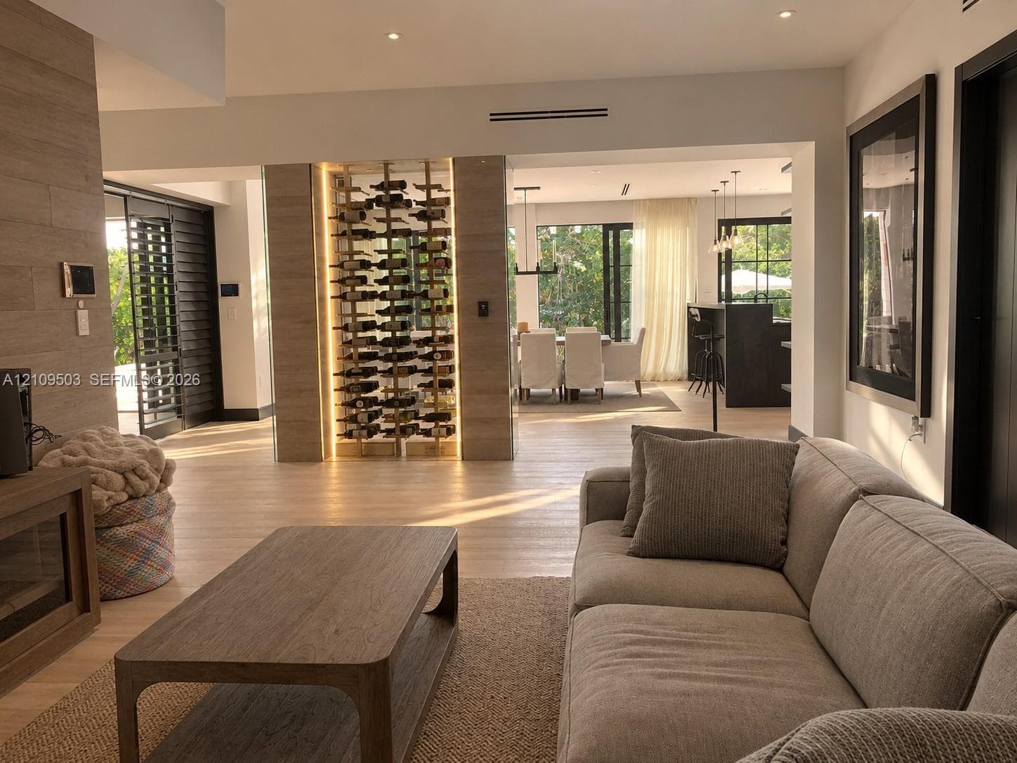 Built-in glass-enclosed wine display with integrated accent lighting, wood-finish flooring, stone-clad feature wall, and recessed ceiling lighting