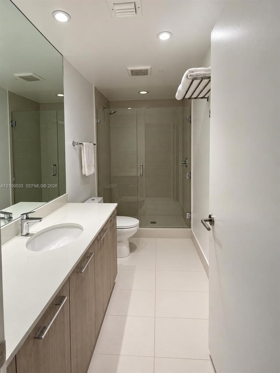 Vanity featuring a light wood-finish cabinet, white solid-surface countertop, and an integrated basin with a polished chrome faucet