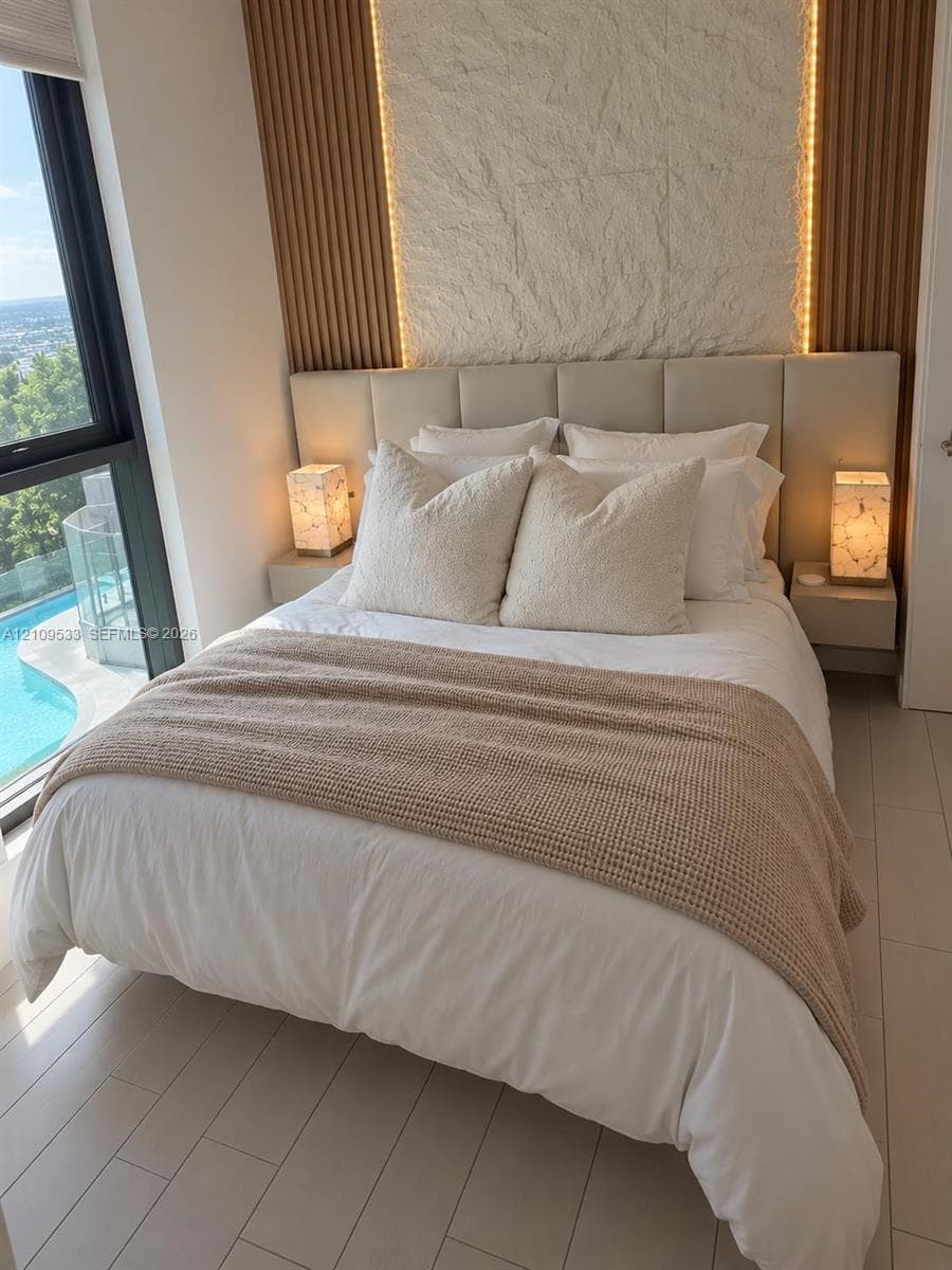 Floor-to-ceiling windows, vertical wood-slat wall paneling, integrated stone accent wall, light-toned tile flooring, and wall-mounted bedside cabinetry
