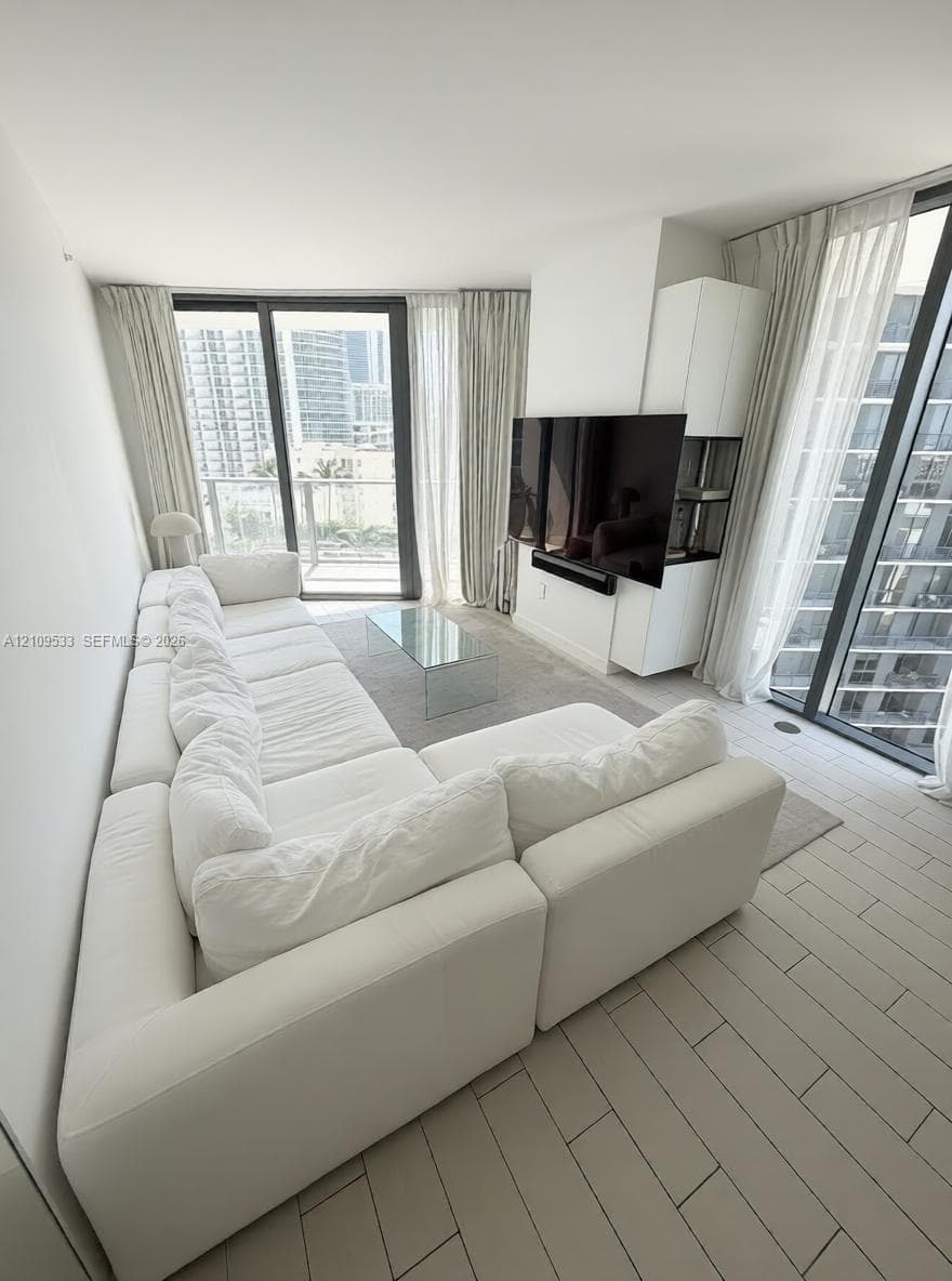 Floor-to-ceiling glass panel walls, custom built-in white cabinetry, and light-toned tile flooring throughout
