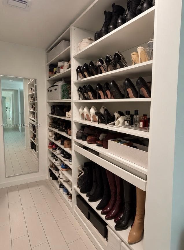 Custom floor-to-ceiling white shelving with multiple storage tiers and a full-length wall mirror